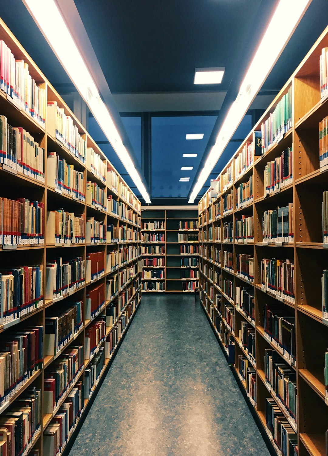 Narrow aisle between tall library bookshelves
