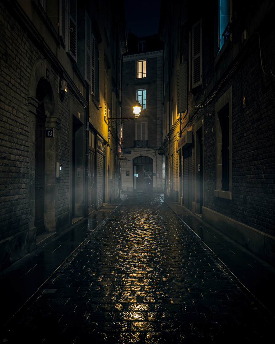 Dark narrow alley at night with a single light